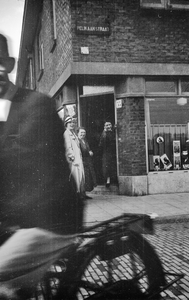 818343 Afbeelding van Mientje Wouda in de deuropening van de kruidenierswinkel van haar ouders (Pelikaanstraat 35) te ...
